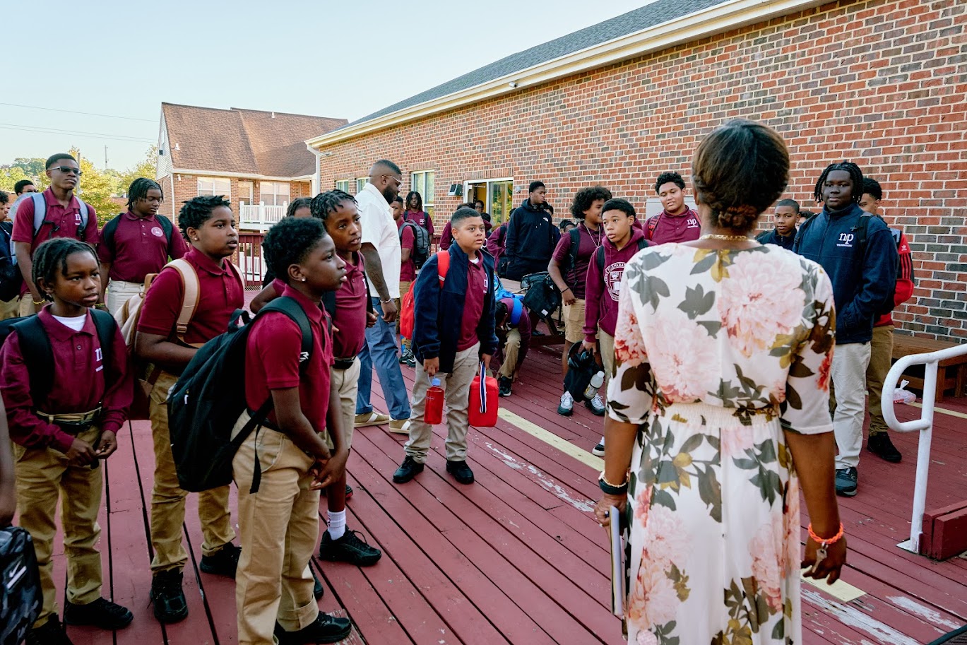 students listening to an educator before school begins.