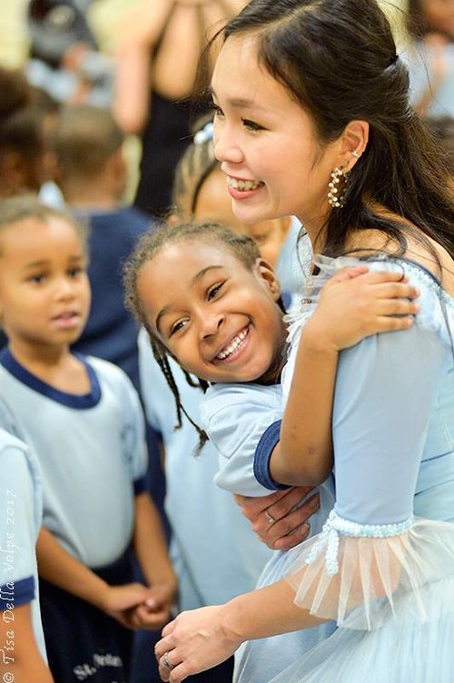children hugging their dance instructor following a performance.