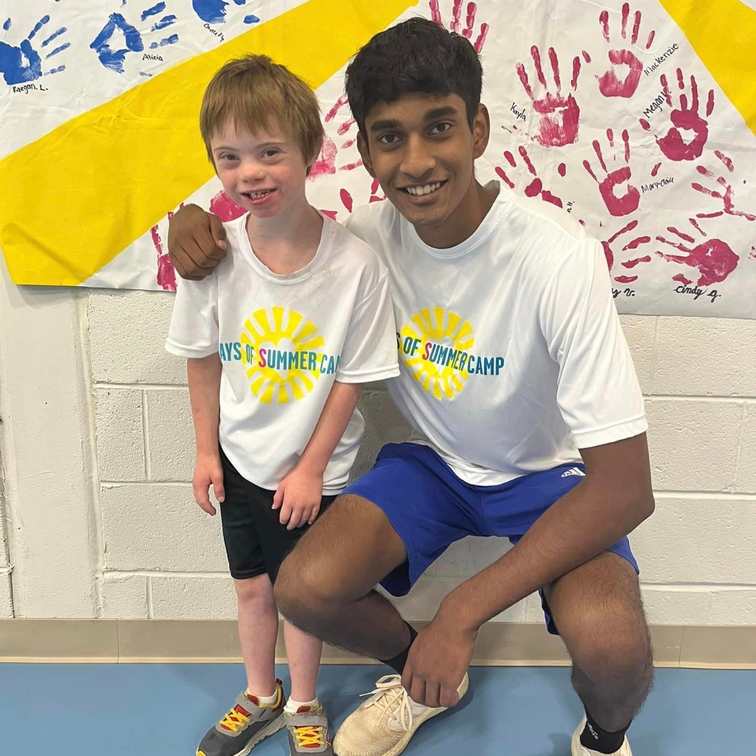a teen participant with a young child posing in front of a camera.