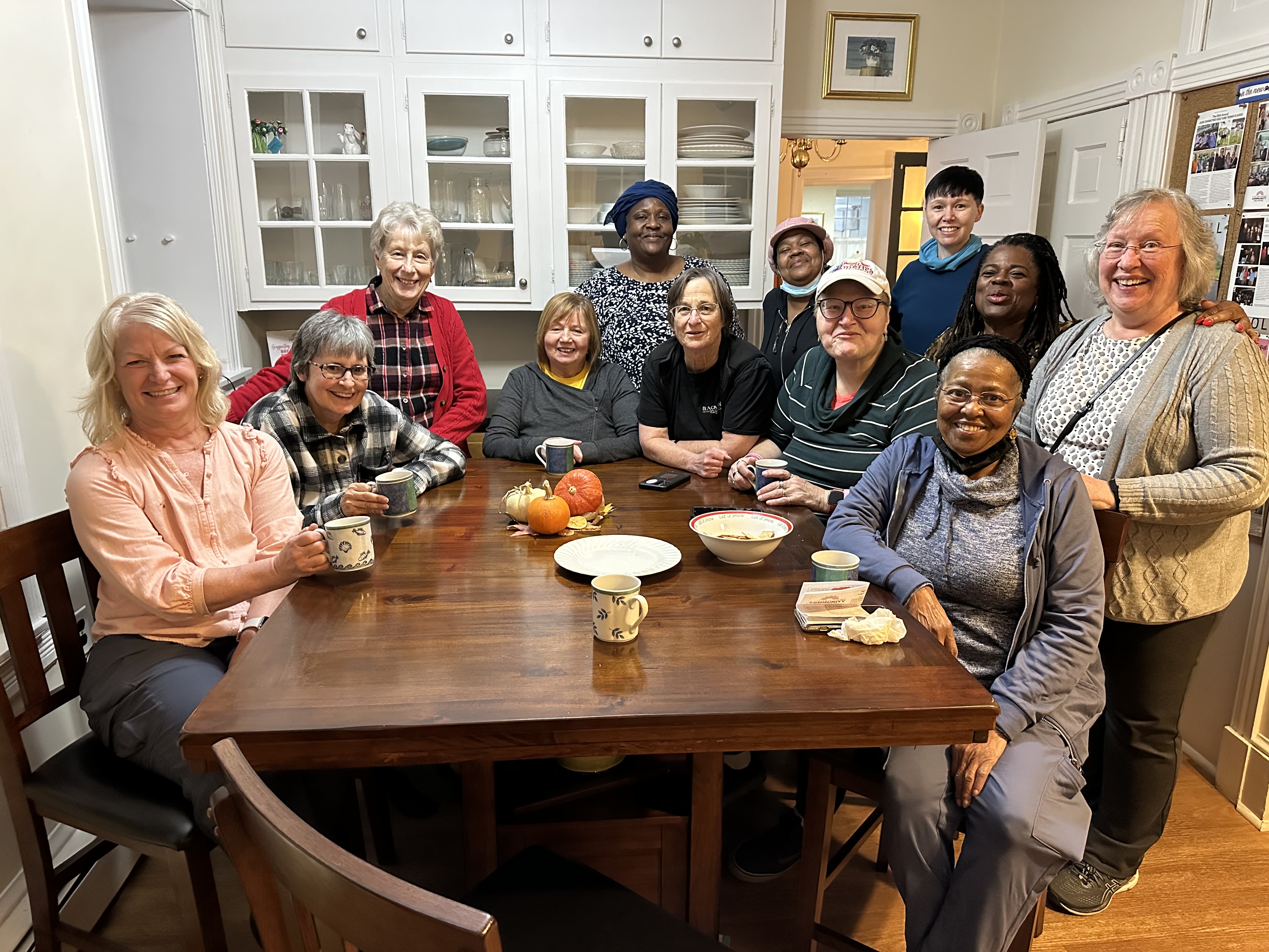 a group of patients sitting in a home kitchen posing for a photo.
