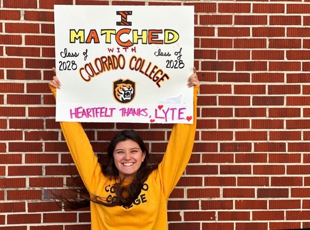 a student holding a college acceptance sign