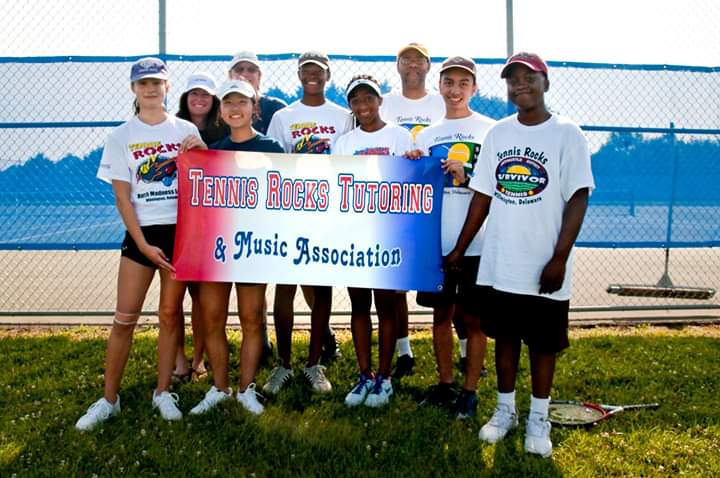 youth posing in front of a sign that reads Tennis Rocks Tutoring