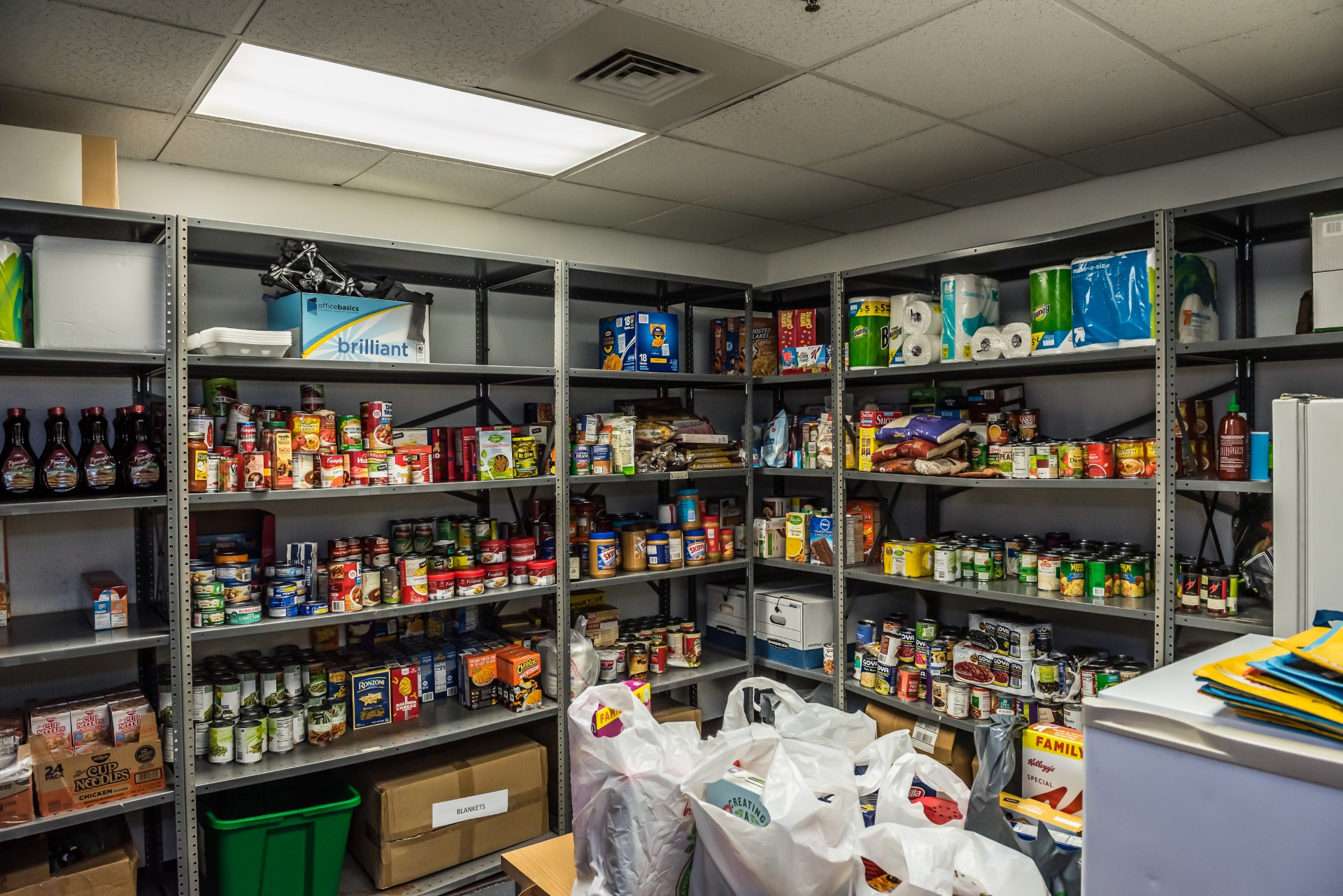 shelves of toiletries and canned food items sit in a donation room.