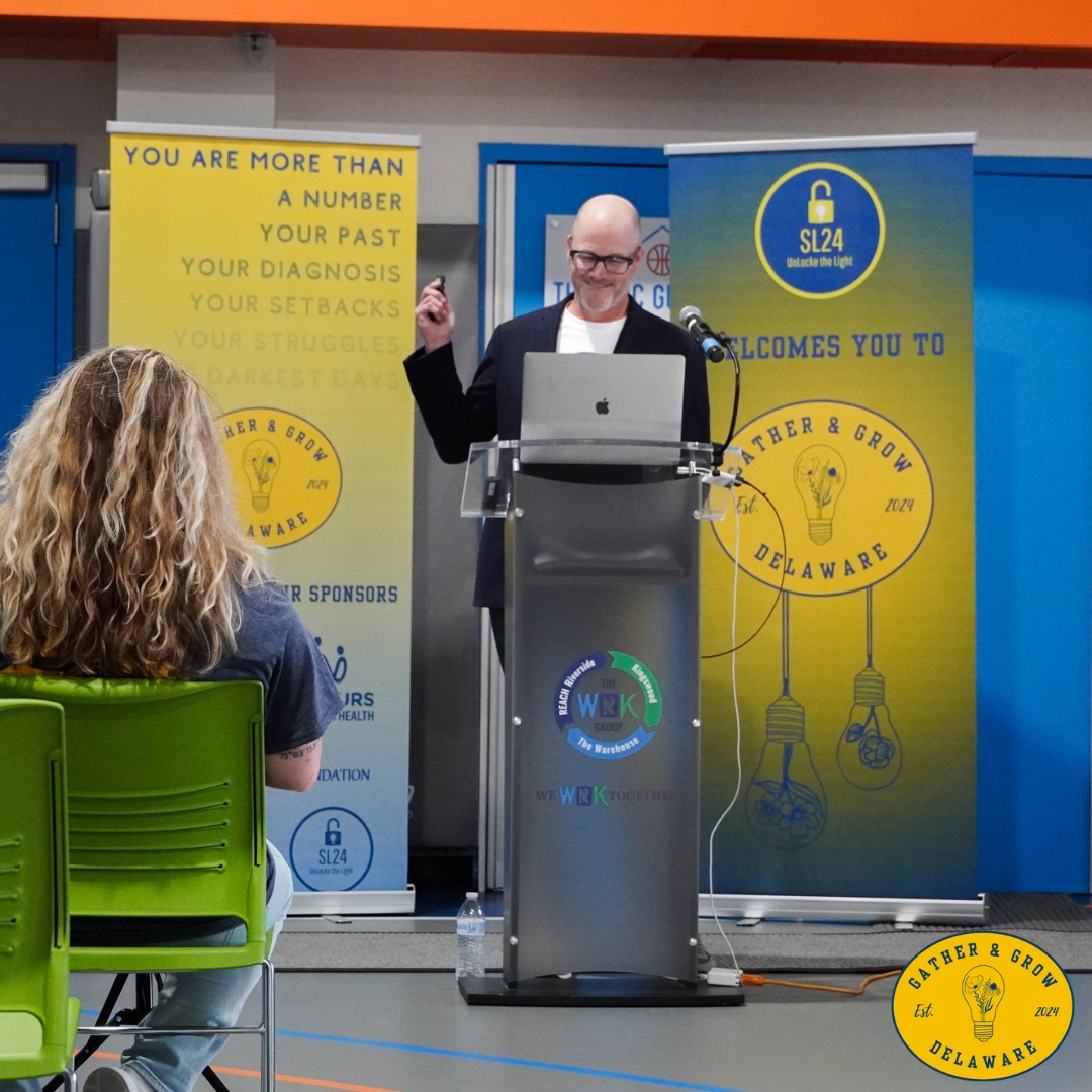 A speaker provides an opening presentation in front of a podium at a seminar for youth.