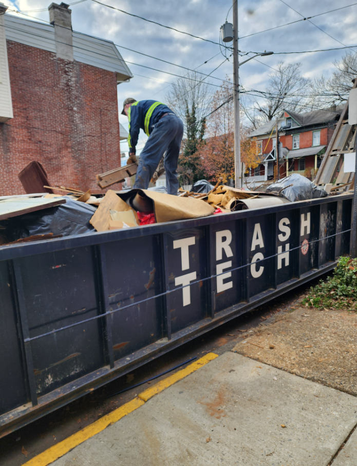 A person stands amid a construction site's disposal for wood pieces and particles discarded.