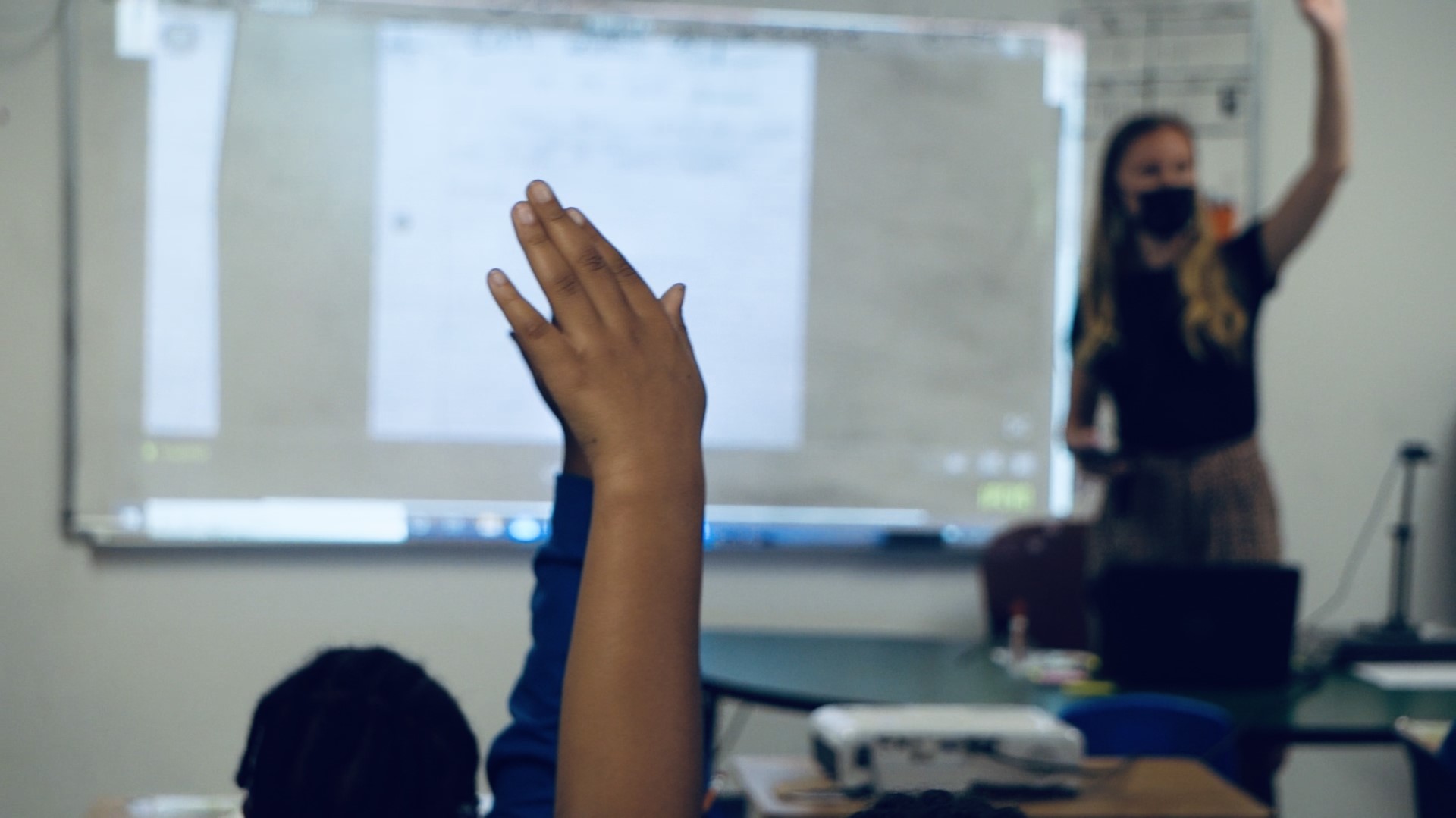 students raising their hand in a classroom