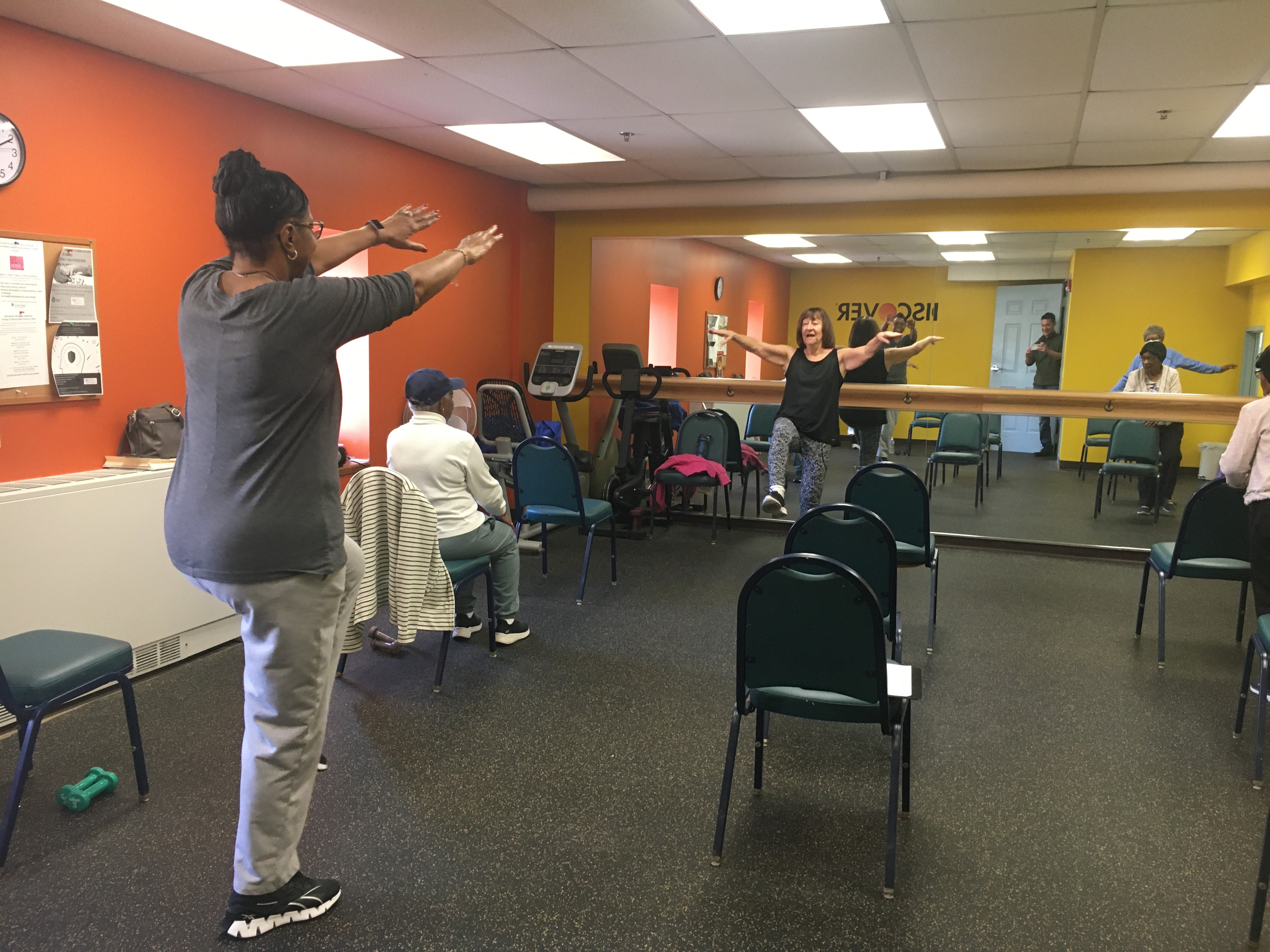 individuals participate in a workout room with a dance instructor.