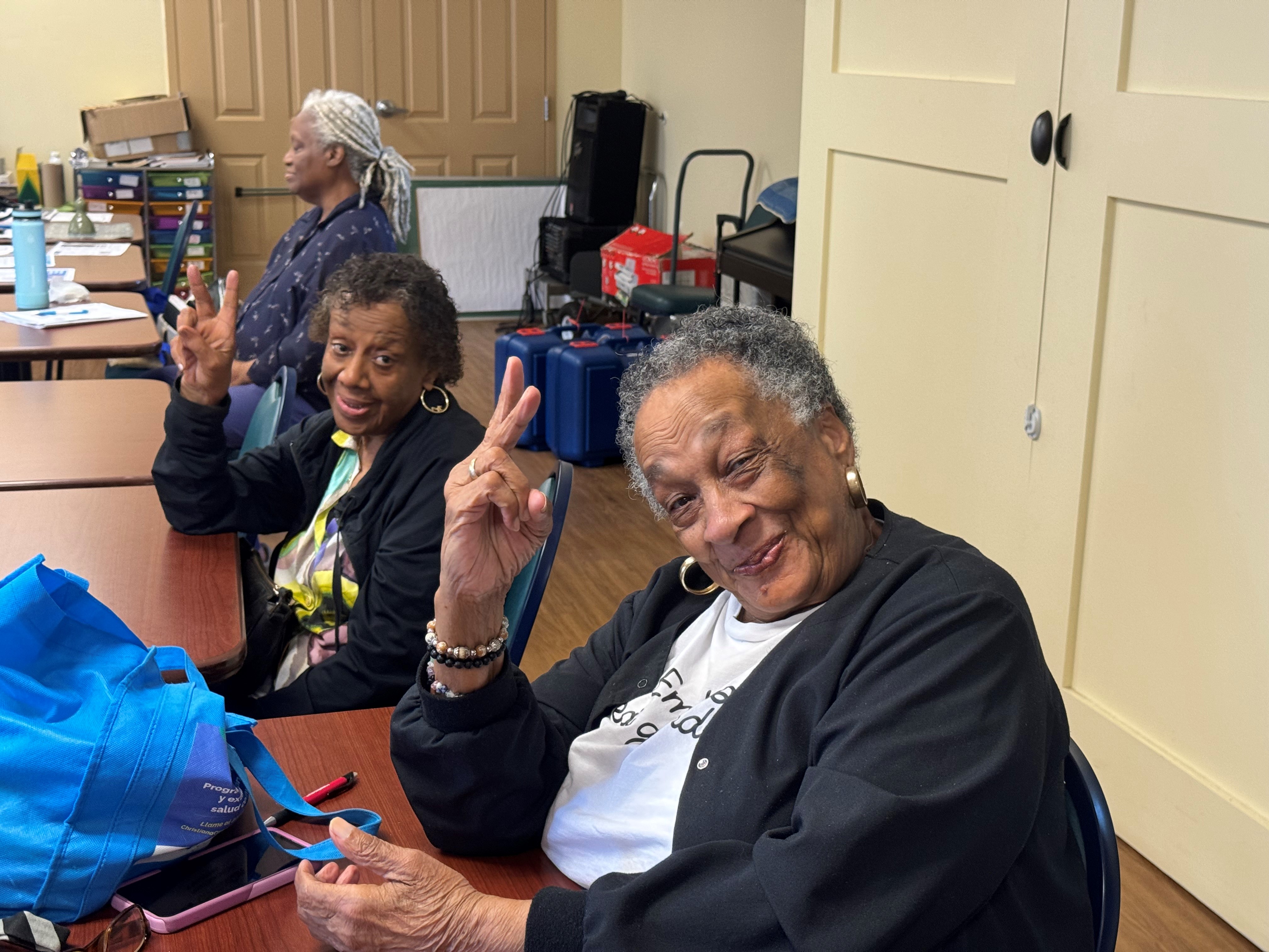 individuals pose with a peace sign to the camera.