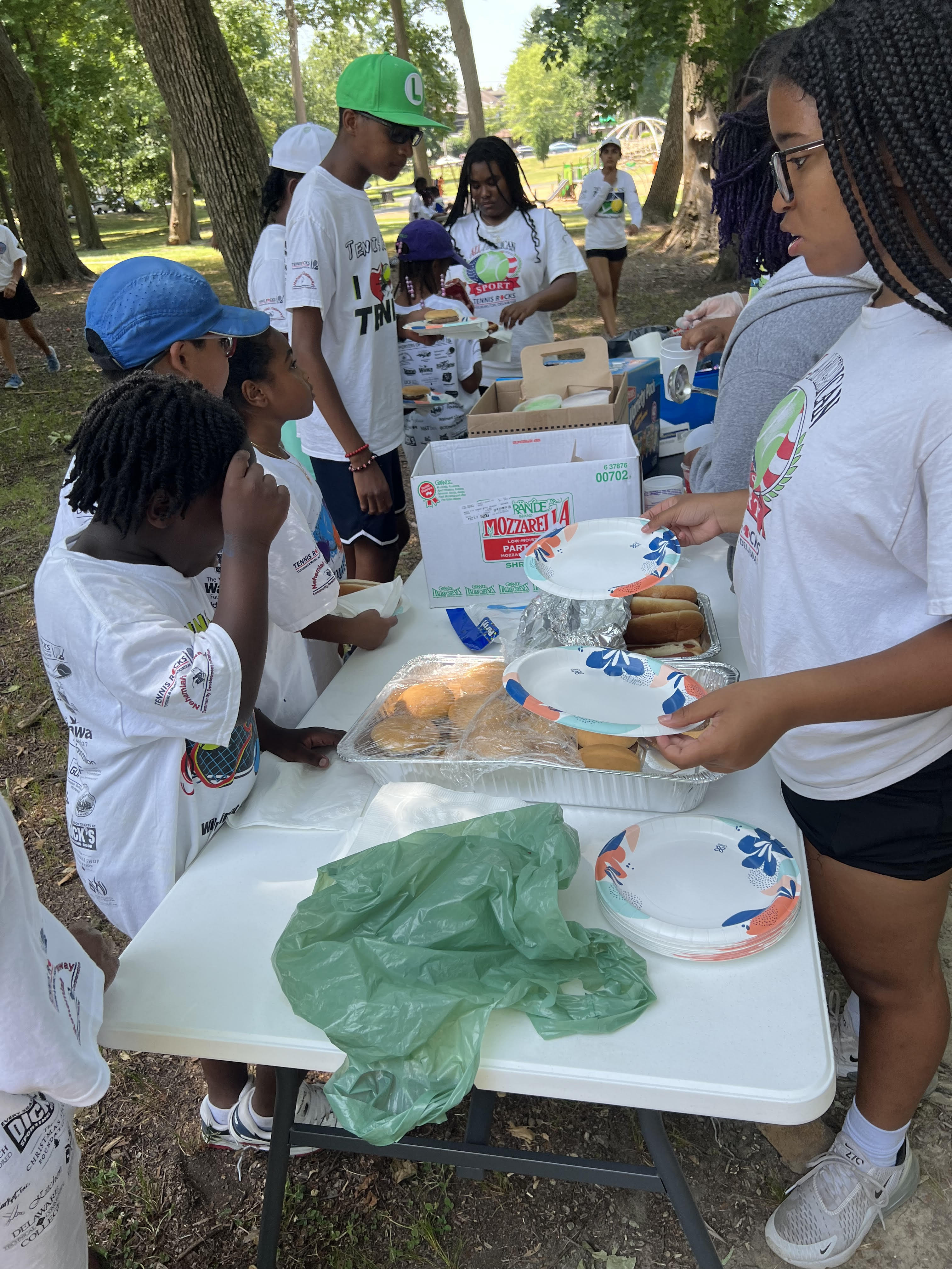 teenagers supporting young children at a summer park program