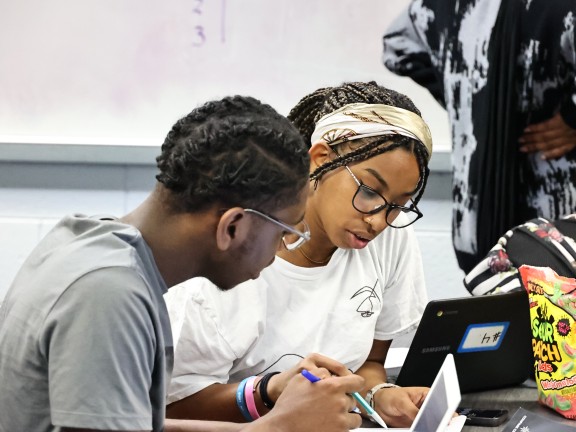 students at a university looking over notes in a classroom