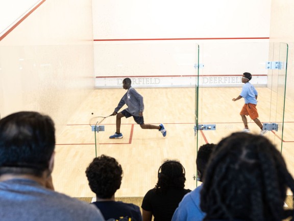 two players playing squash while observers watch in crowd