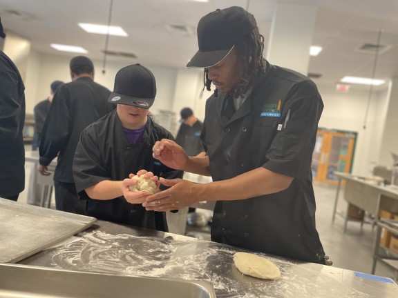 two persons in a culinary class making dough.