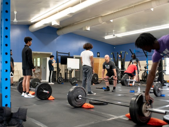 youth lifting weights in a gym with an instructor