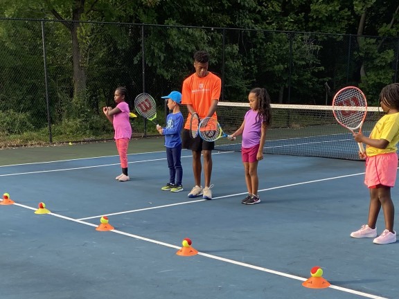 children playing tennis with an instructor.