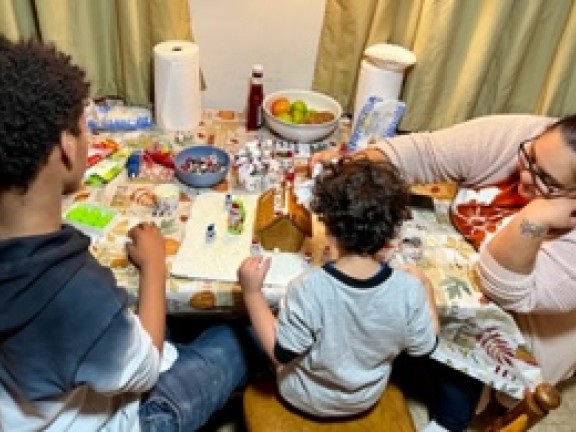children sitting with a parent at the table working on crafts