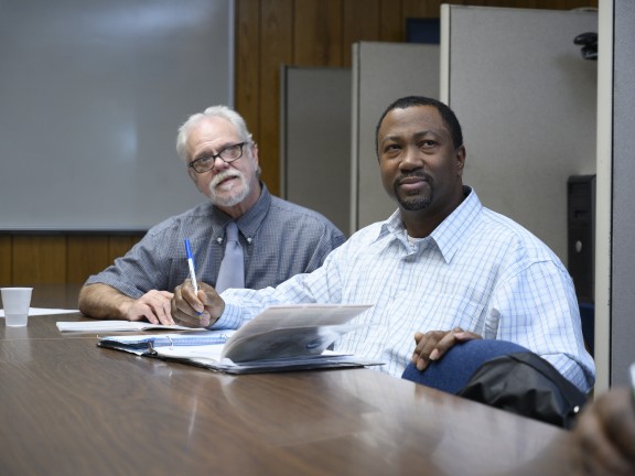 two persons sitting at a conference room table.