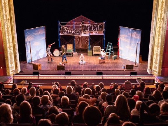 children seated in an auditorium for a play.