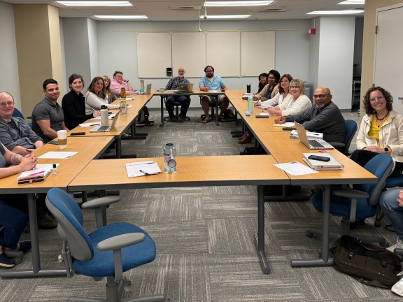 A group of committee representatives sitting in a conference room posing for the camera.