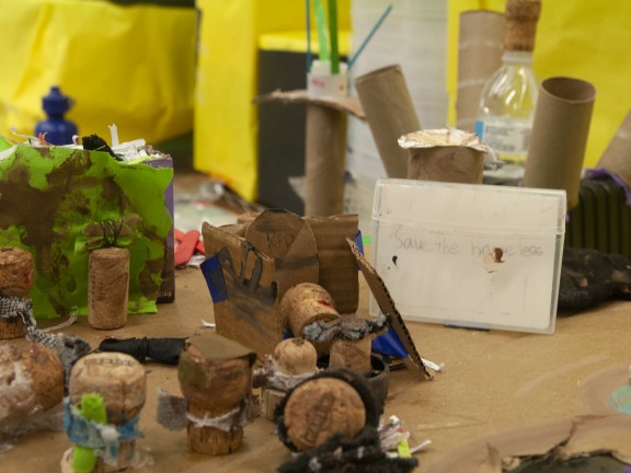 an art display made of papertowel rollers and other arts and crafts sit on a workshop table.