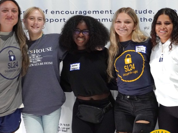 youth posing in front of a wall backdrop while at a mental health summit