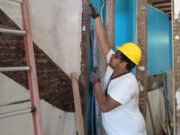 a construction worker wearing a hardhat remodels the interior of a home.