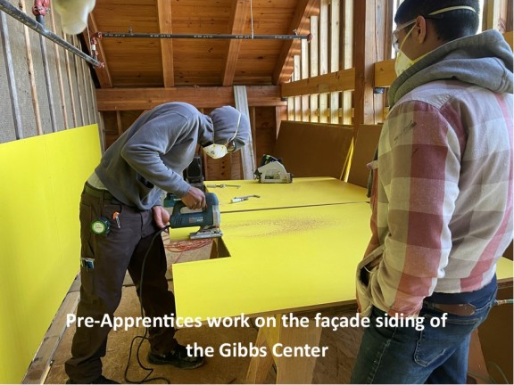 pre-apprentices work on the material siding for a new center