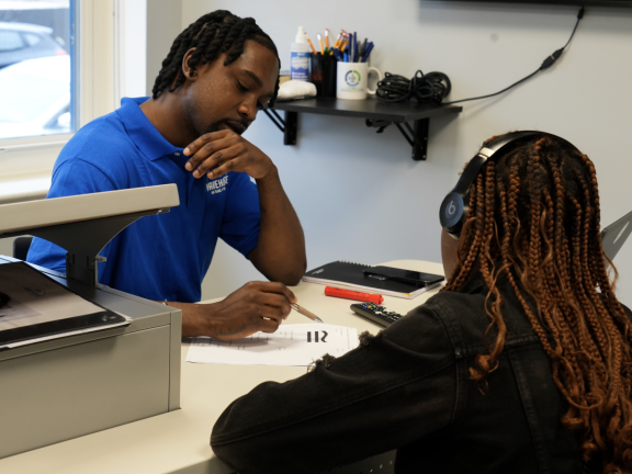 A worker and teenager sitting at a desk