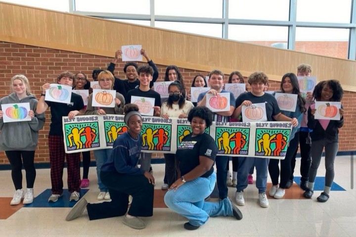 a group of Best Buddies ambassadors posing in a school with youngsters