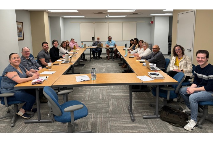 A group of committee representatives sitting in a conference room posing for the camera.