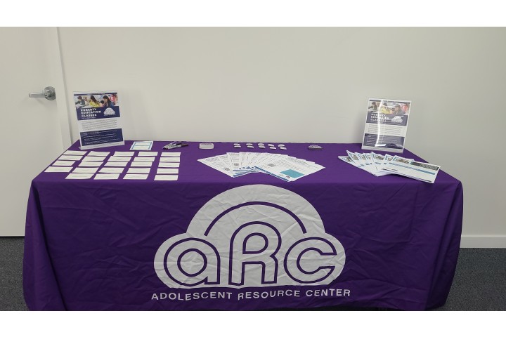 a table displaying resources and literature with a purple tablecloth.