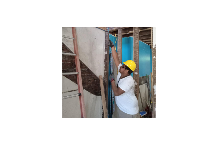 a construction worker wearing a hardhat remodels the interior of a home.