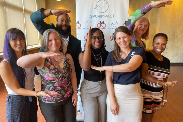 Seven individuals stand to spell the letters 'ELC' for Emerging Leaders Cohort while smiling