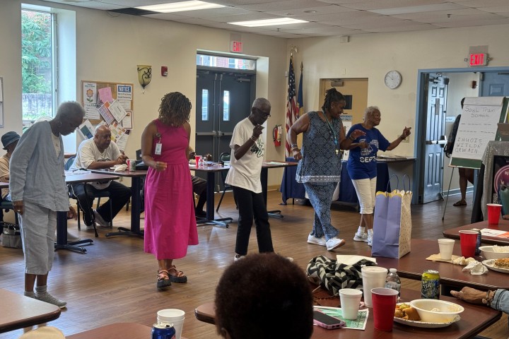 Individuals participating in a line dance while at the Senior Center's recreation and dining room.