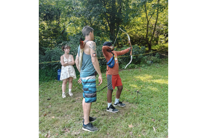 a student and counselor at an archery camp