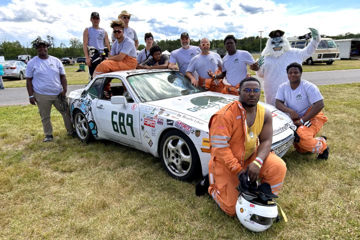 youth posing in front a race car